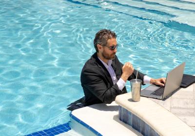 Vakantie ondernemer achter laptop in zwembad