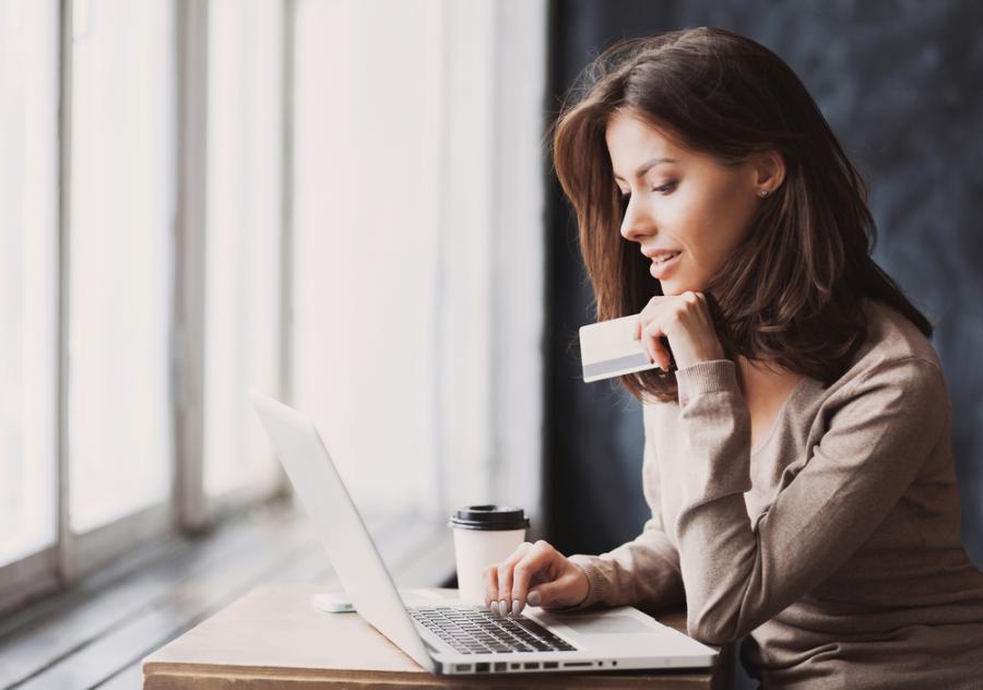 Ondernemer kijkend naar laptop met pinpas in de hand