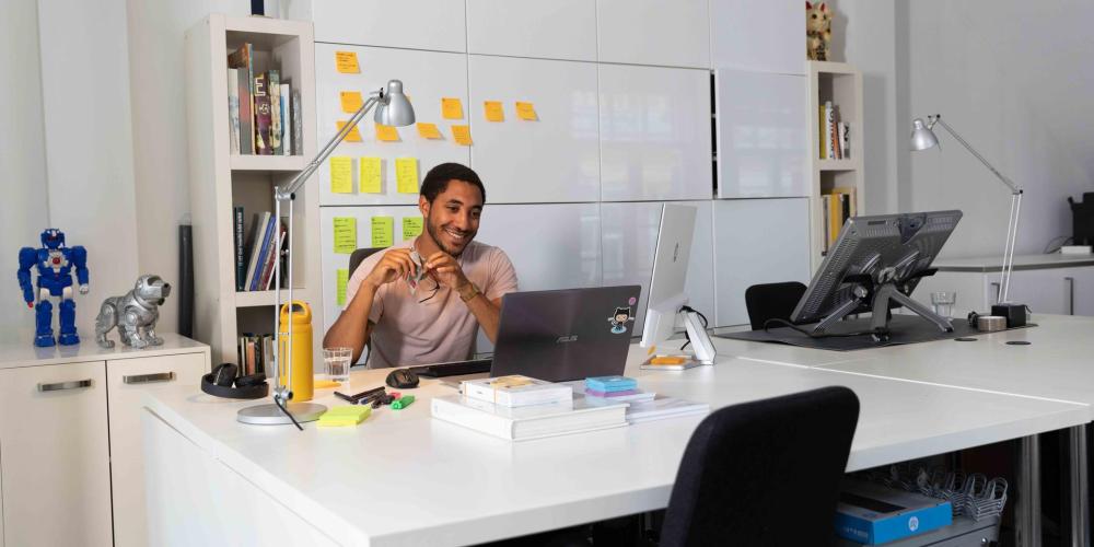 man op kantoor achter bureau en laptop