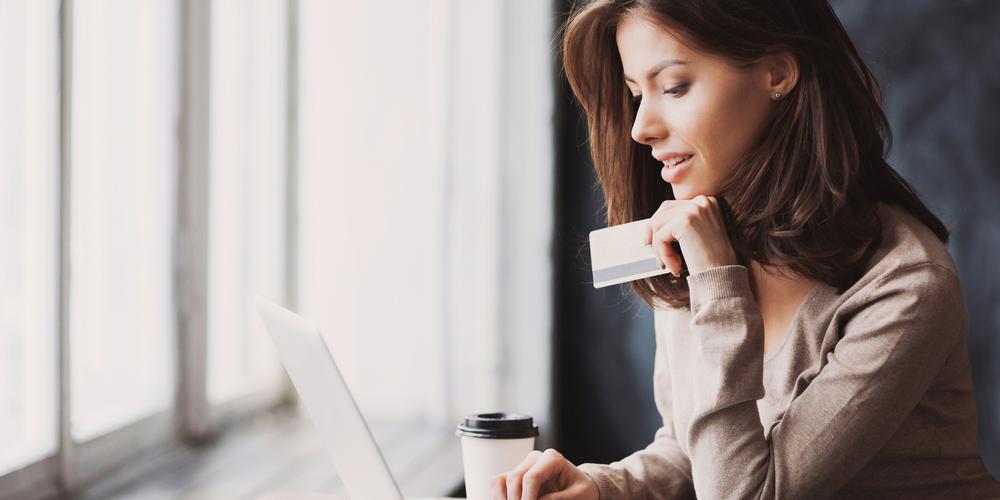 Ondernemer kijkend naar laptop met pinpas in de hand